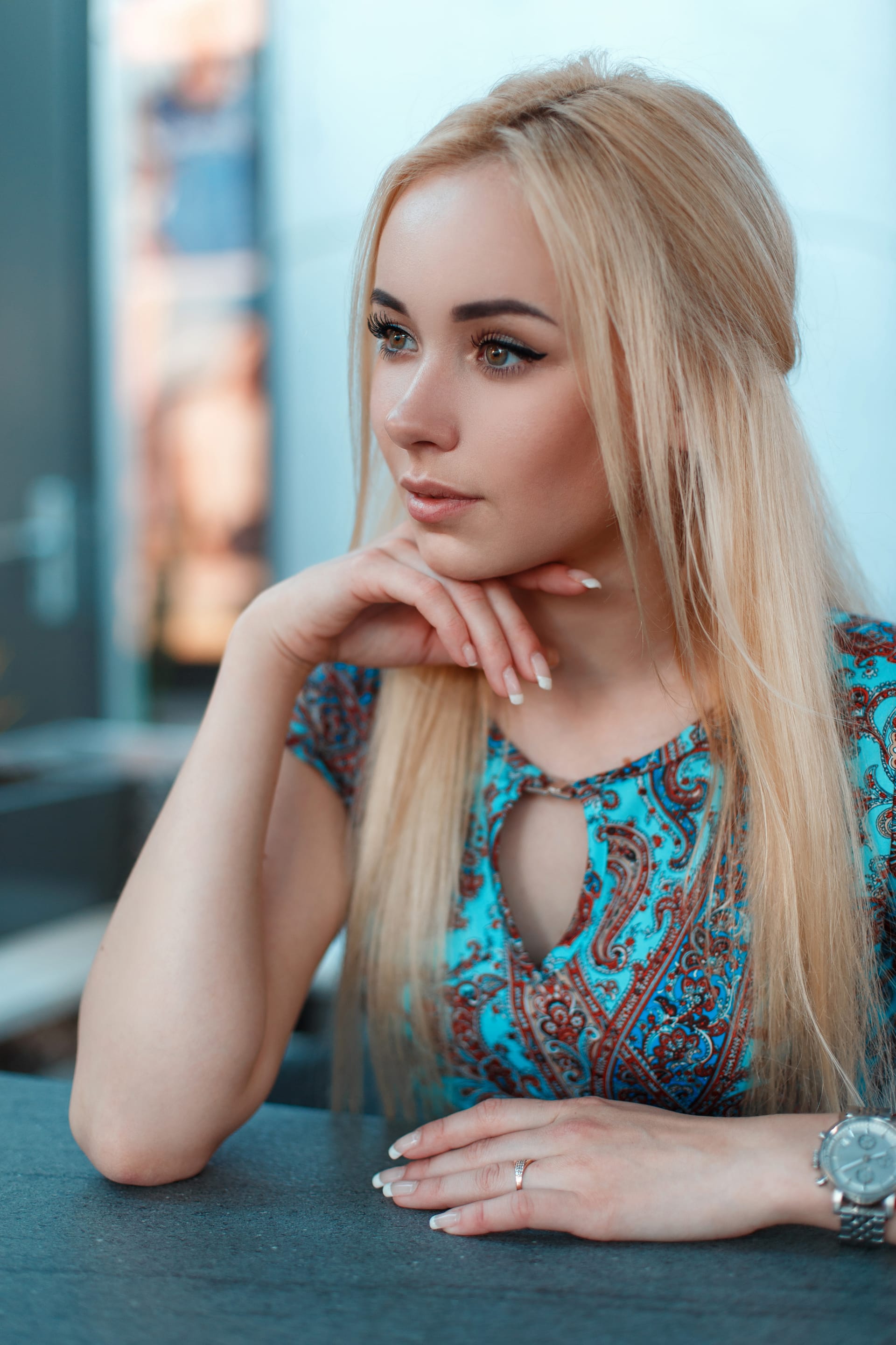 Young blond woman blue dress with pattern sits cafe street