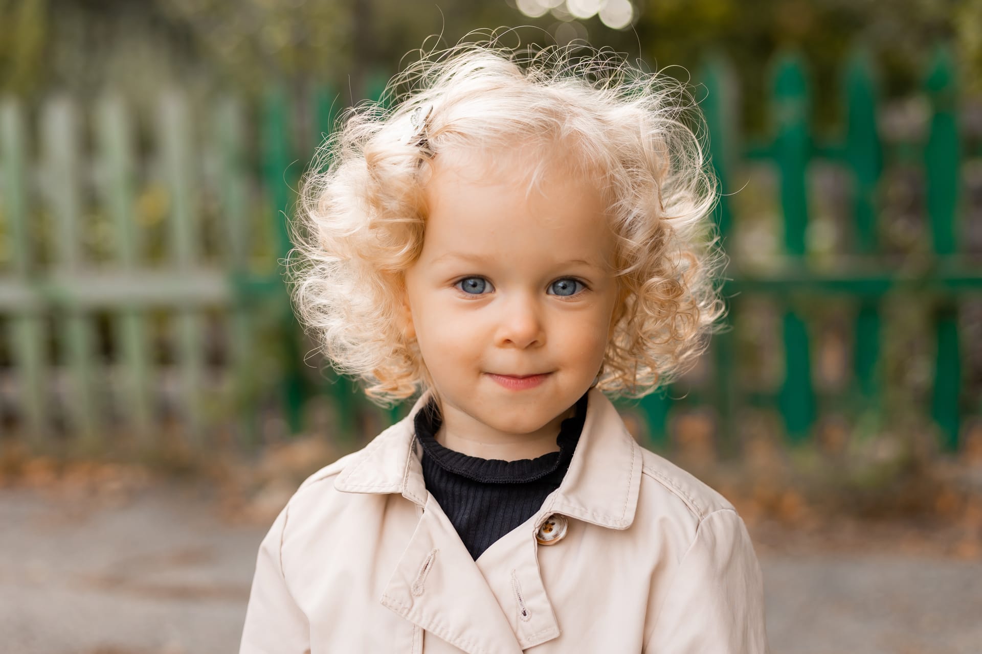 Little curly blonde girl with blue eyes white linen raincoat