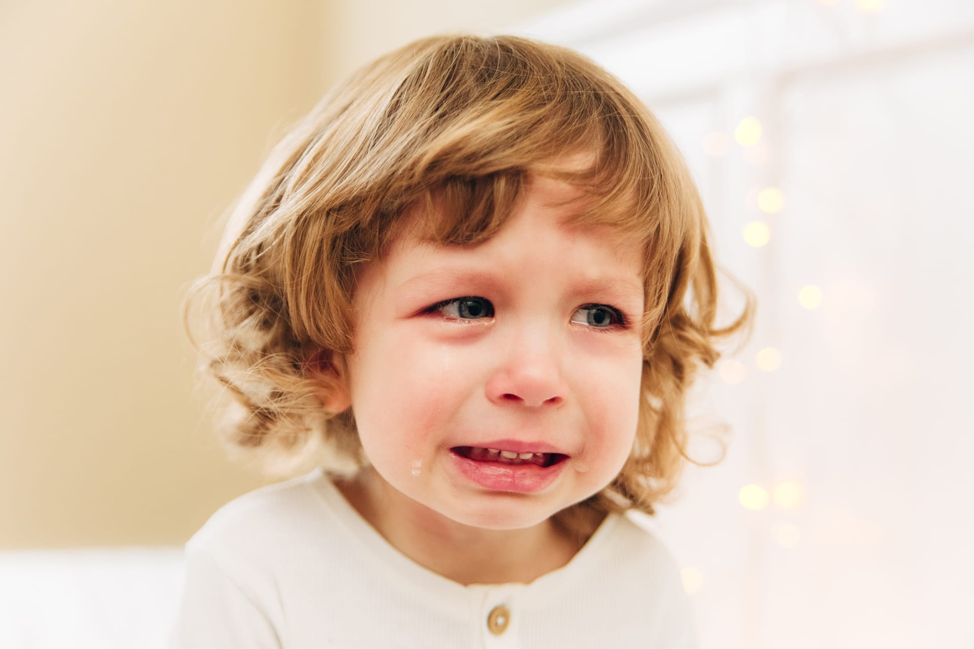 Small cute girl is crying indoor curly hair blue eyes