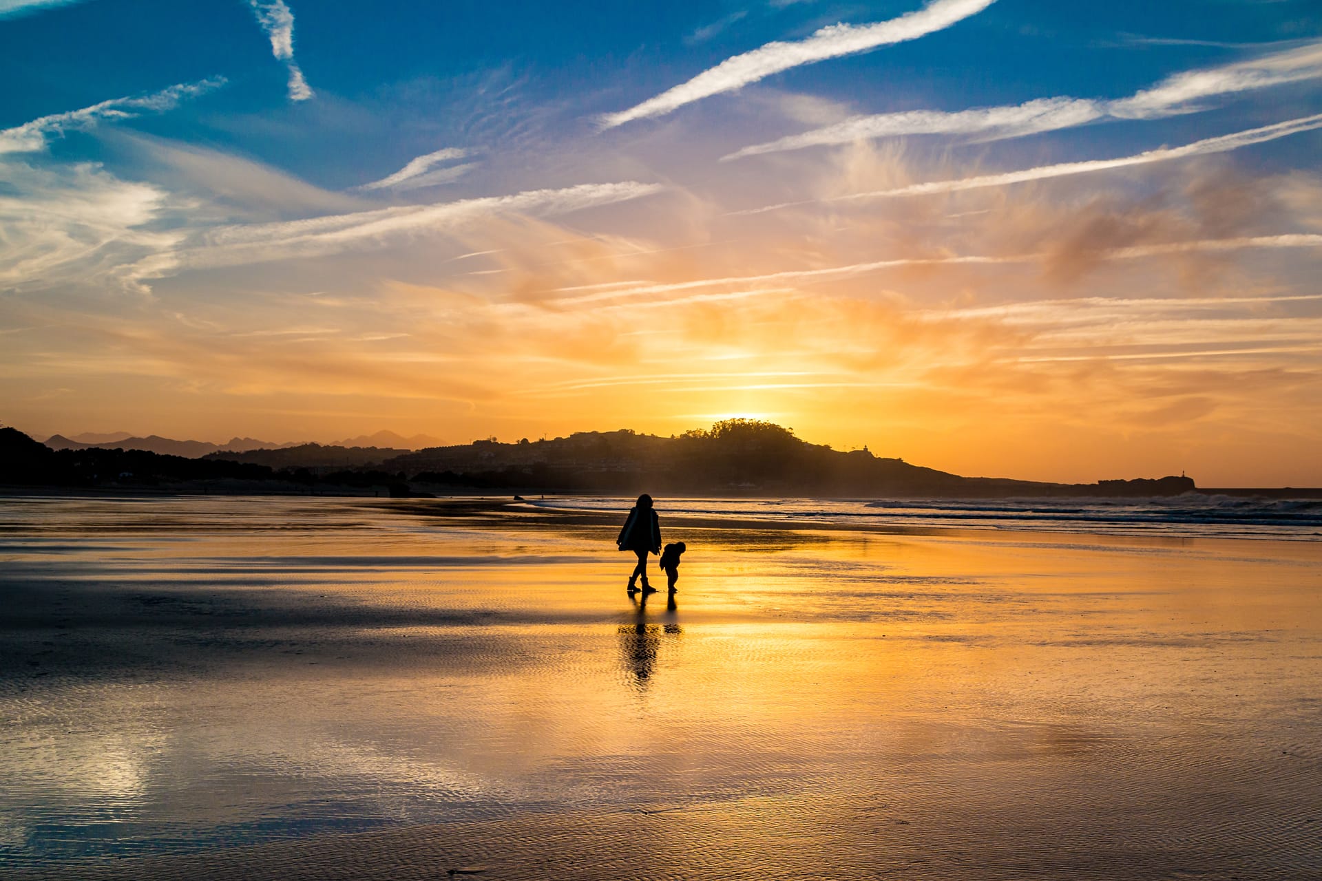 Silhouettes mother child walking beach during stunning sunset winter day