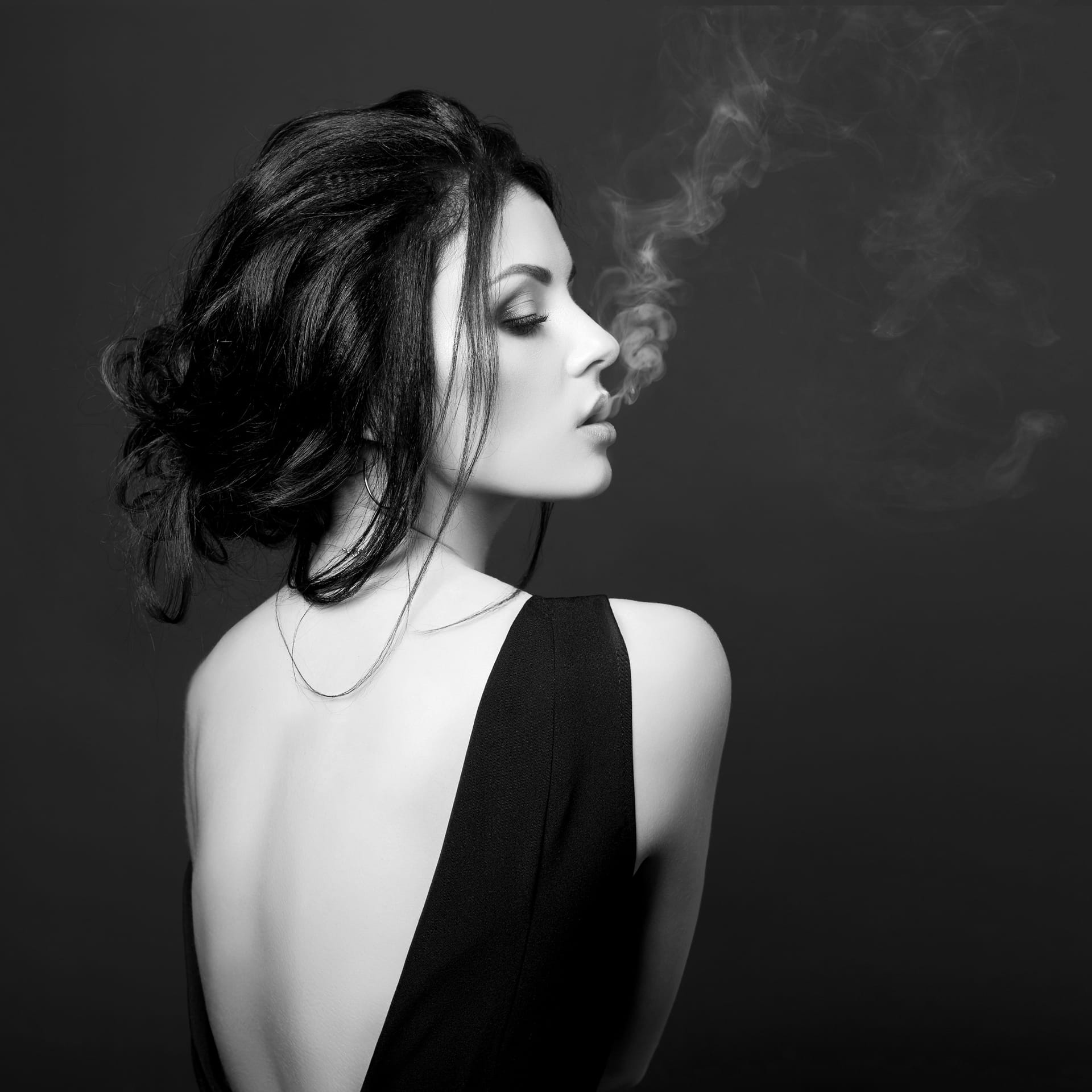 Brunette woman smoking dark background black dress classic portrait confident strong woman