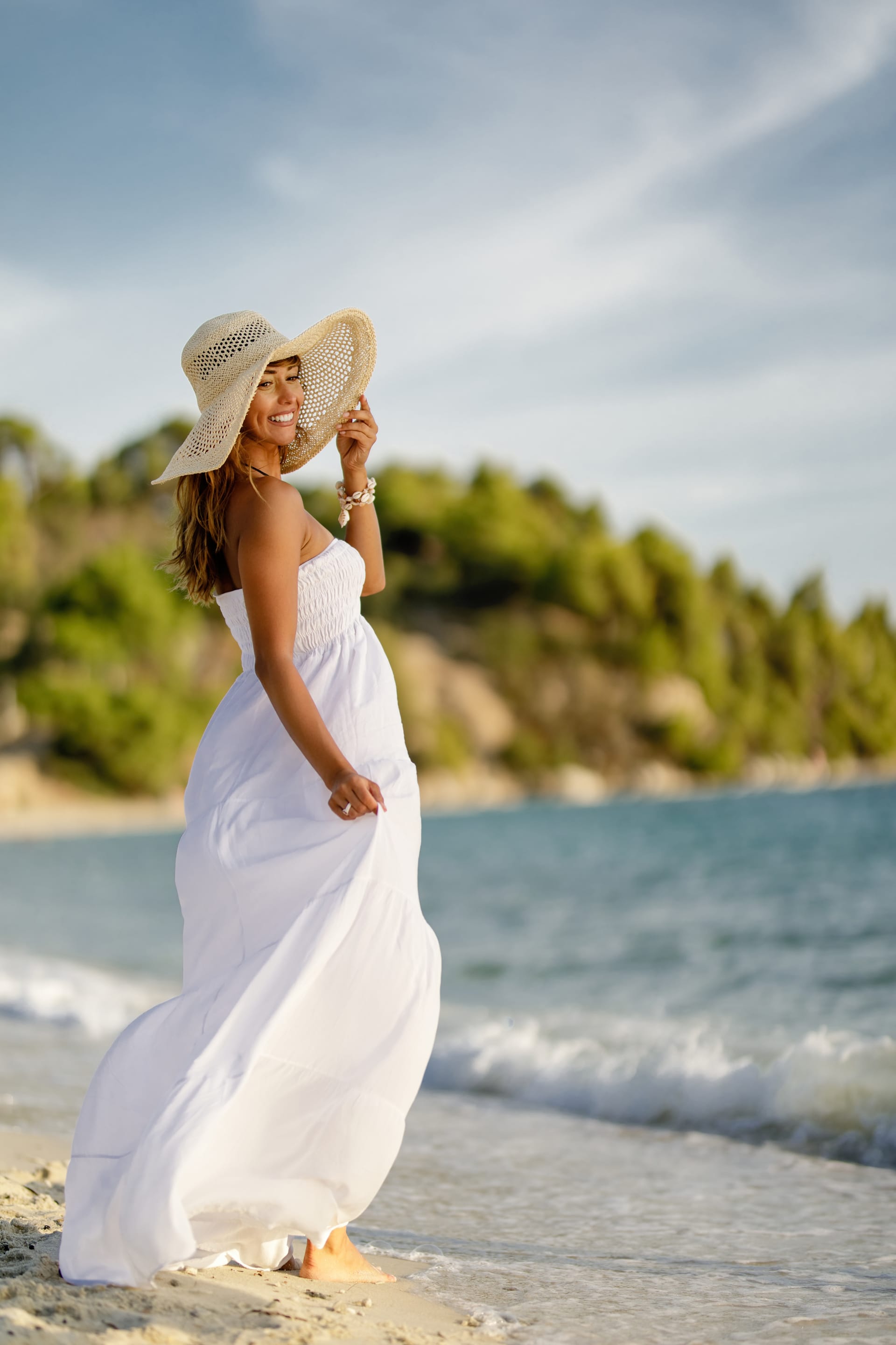 Full length happy woman white dress standing sand beach during summer day