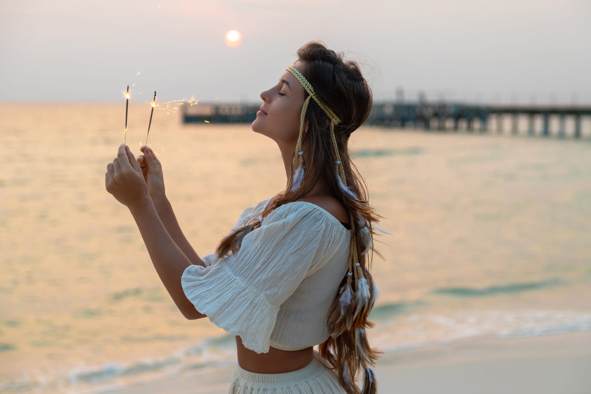 Happy woman with sparklers beach during sunrise