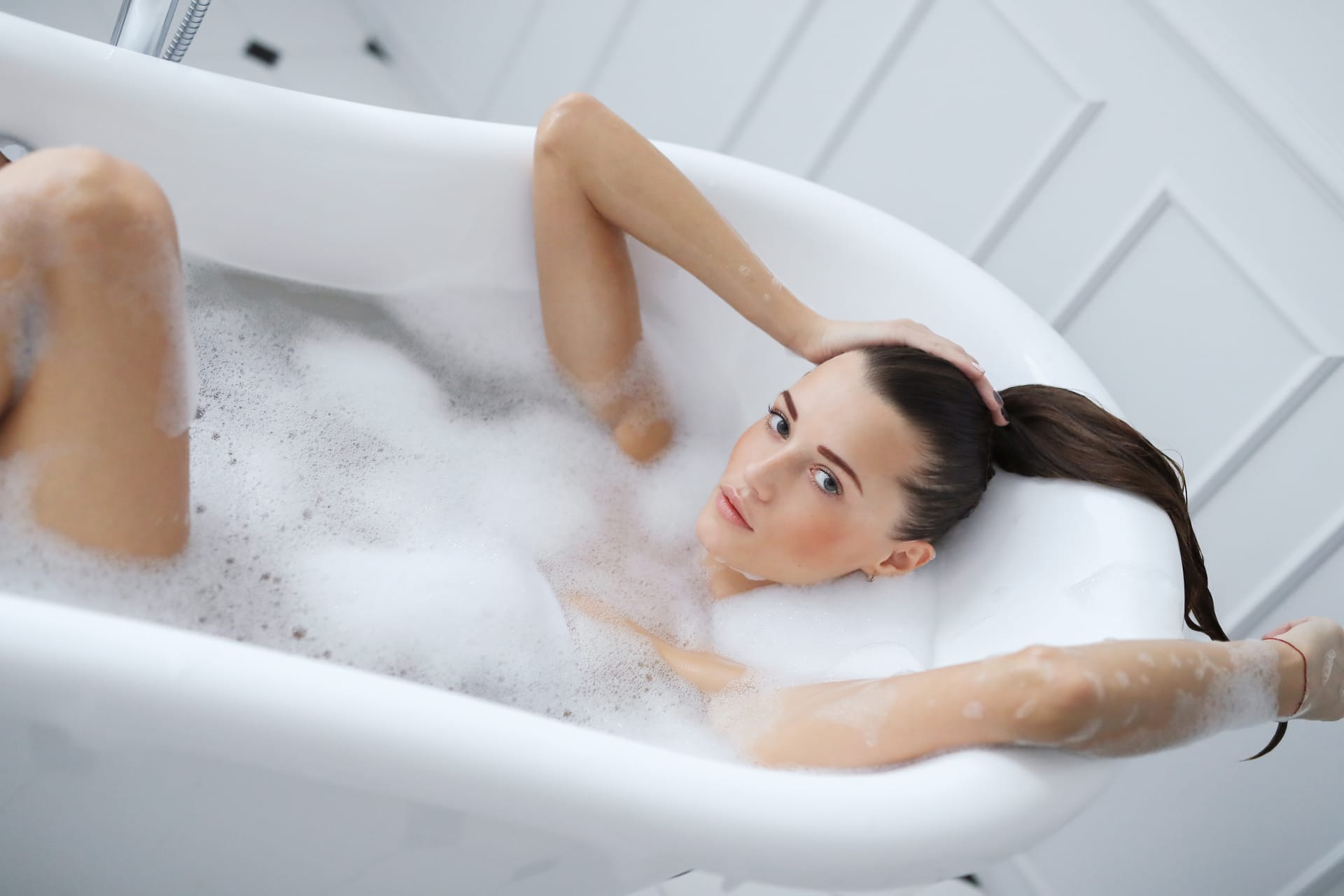 Young nude woman taking relaxing foamy bath