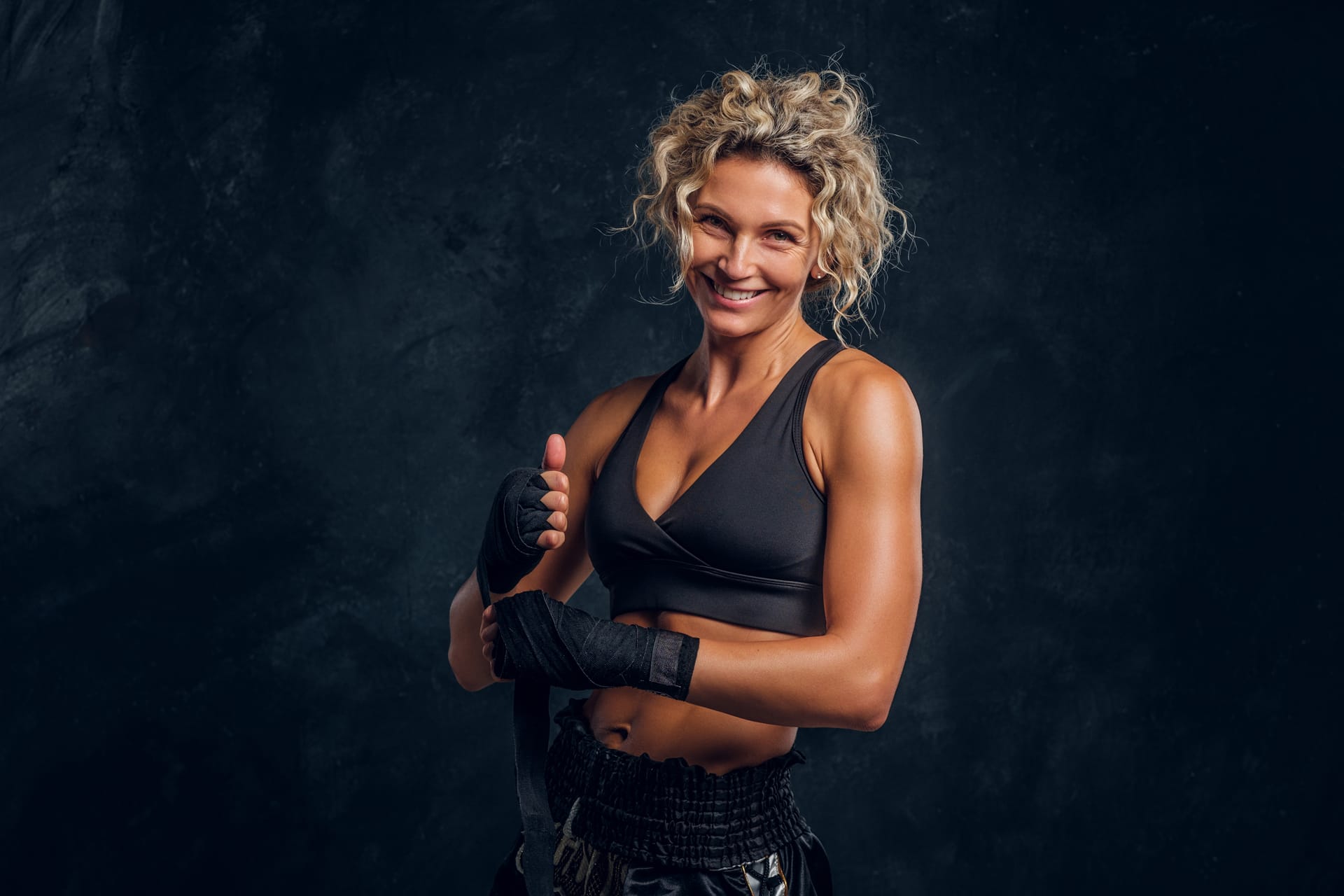 Happy smiling female boxer is posing photographer dark photo studio