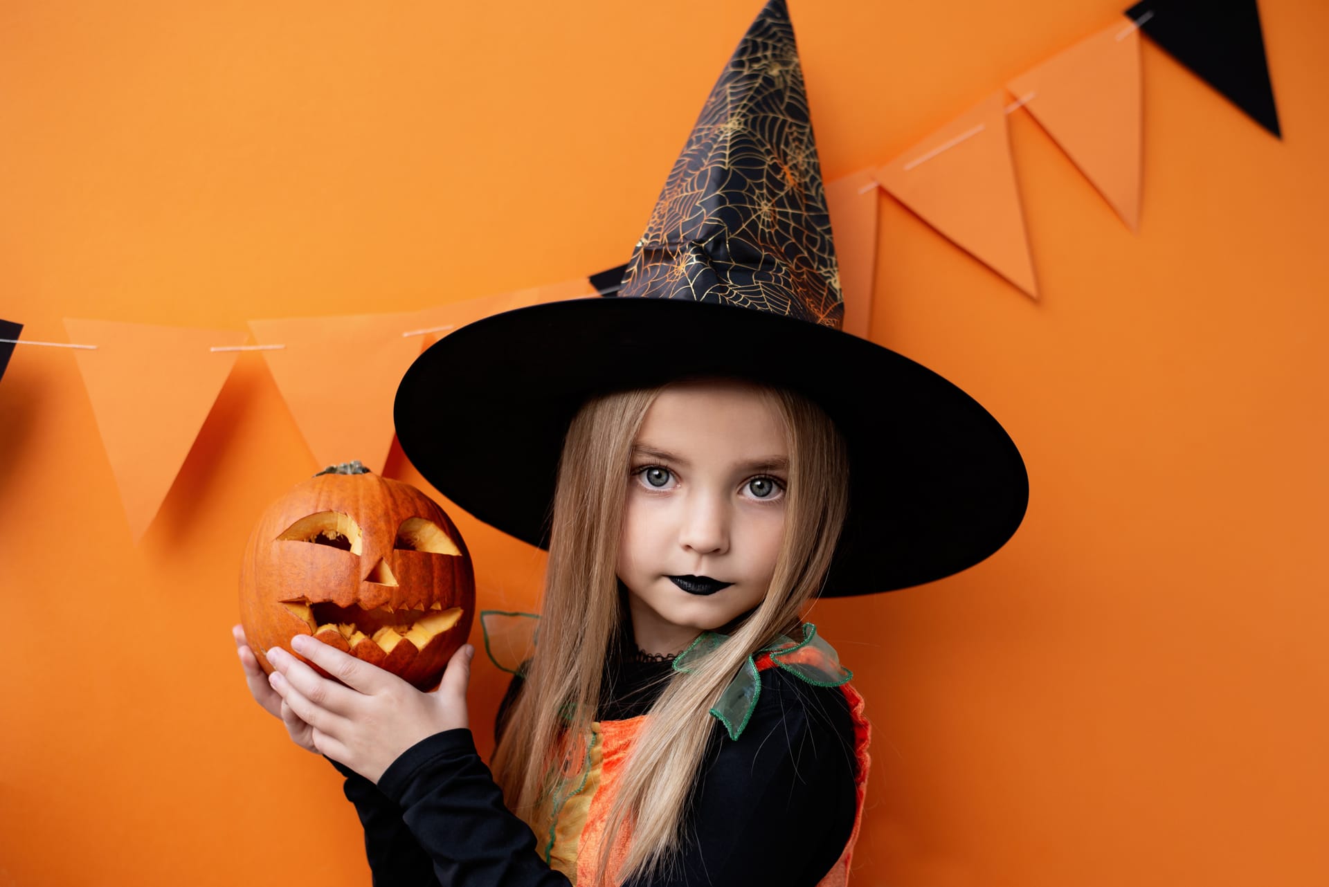 Portrait angry little girl witch costume orange background happy halloween