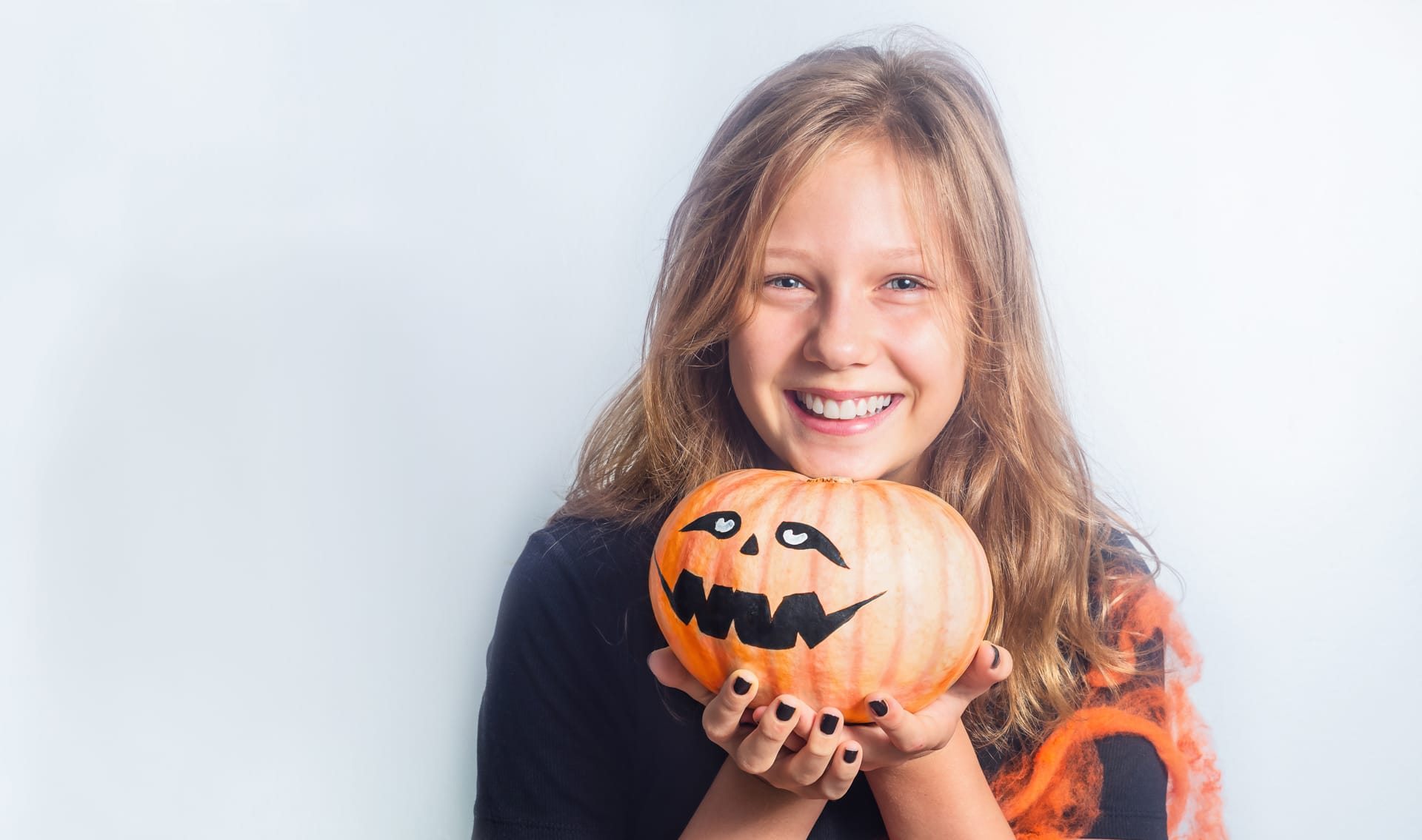 Portrait child with halloween pumpkin hands gray background