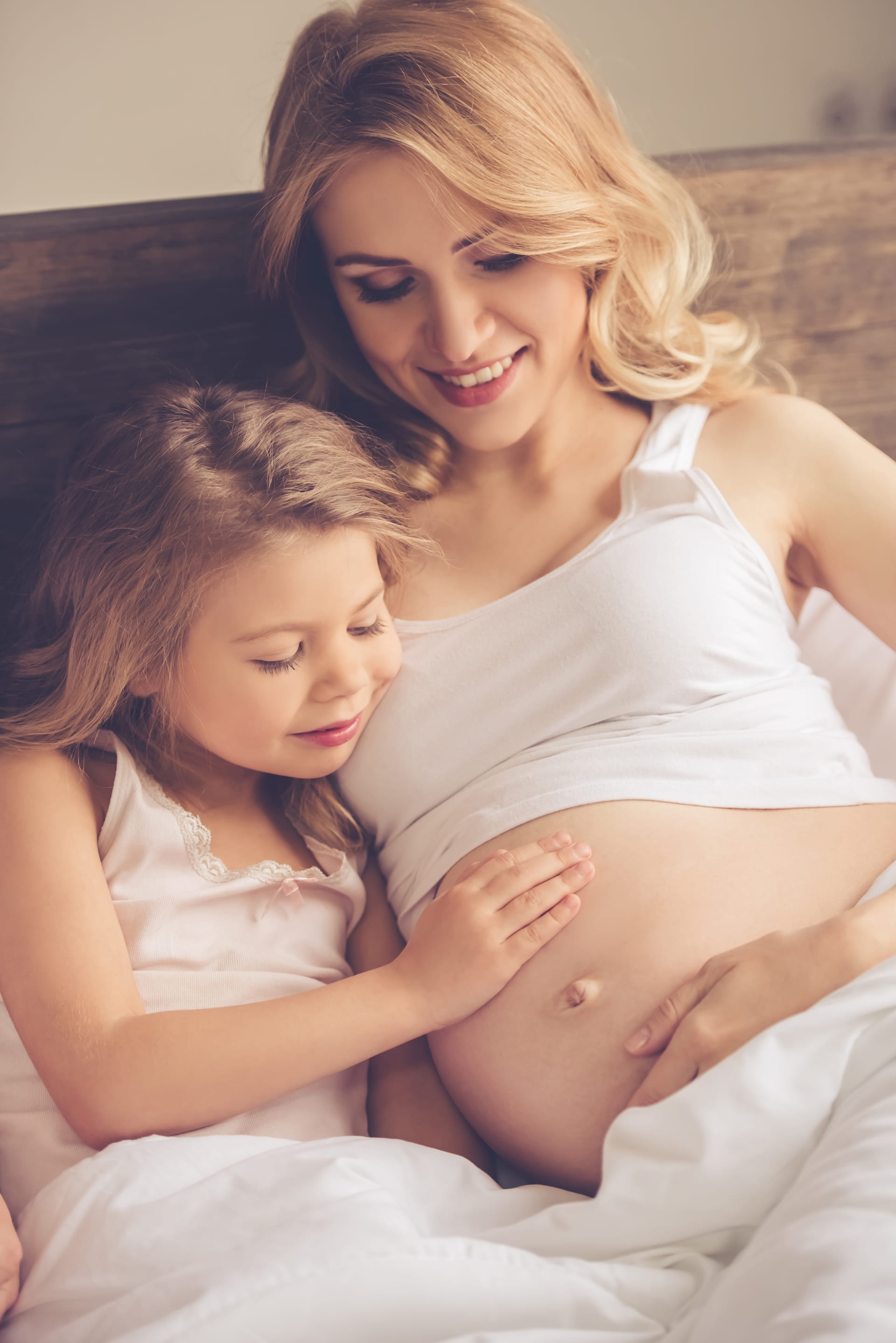Her beautiful pregnant moms belly smiling while spending time together bed