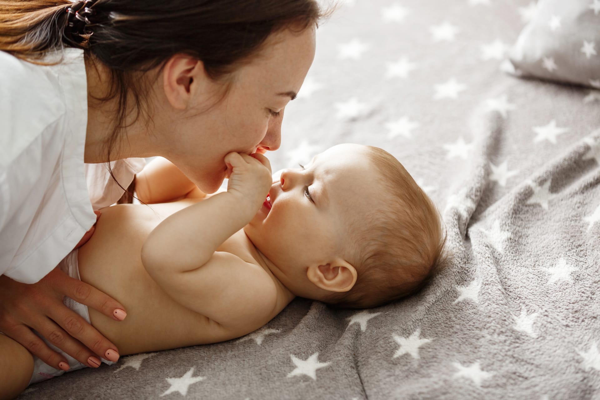 Her newborn son kissing gently biting his little hands happy motherhood concept