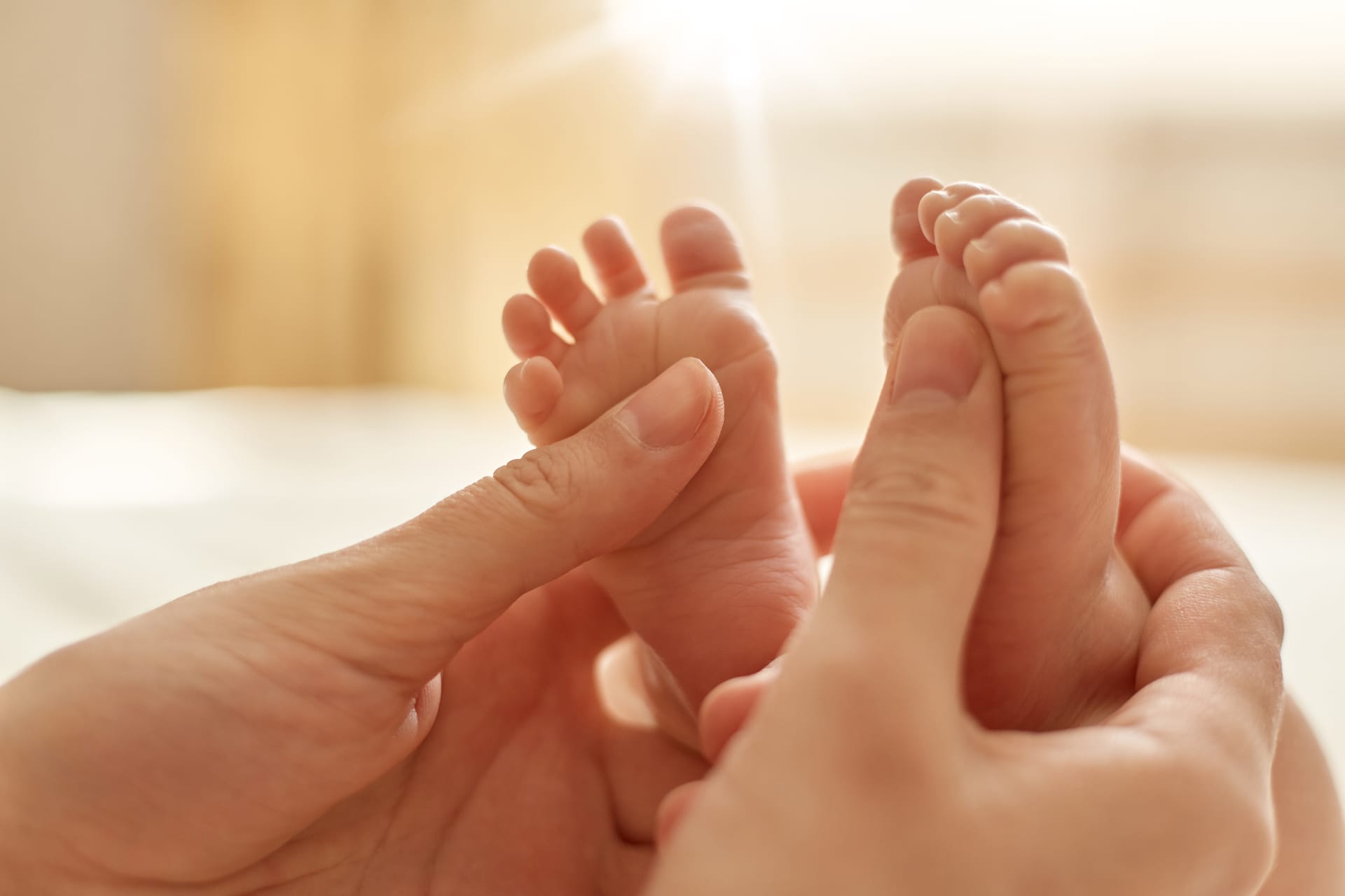 Massage newborn mommy stroking baby s feet with both hands light background