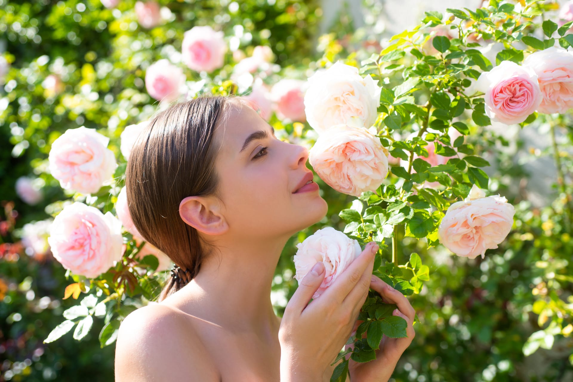 Beautiful young woman posing near roses spring garden candid lifestyle portrait happy young