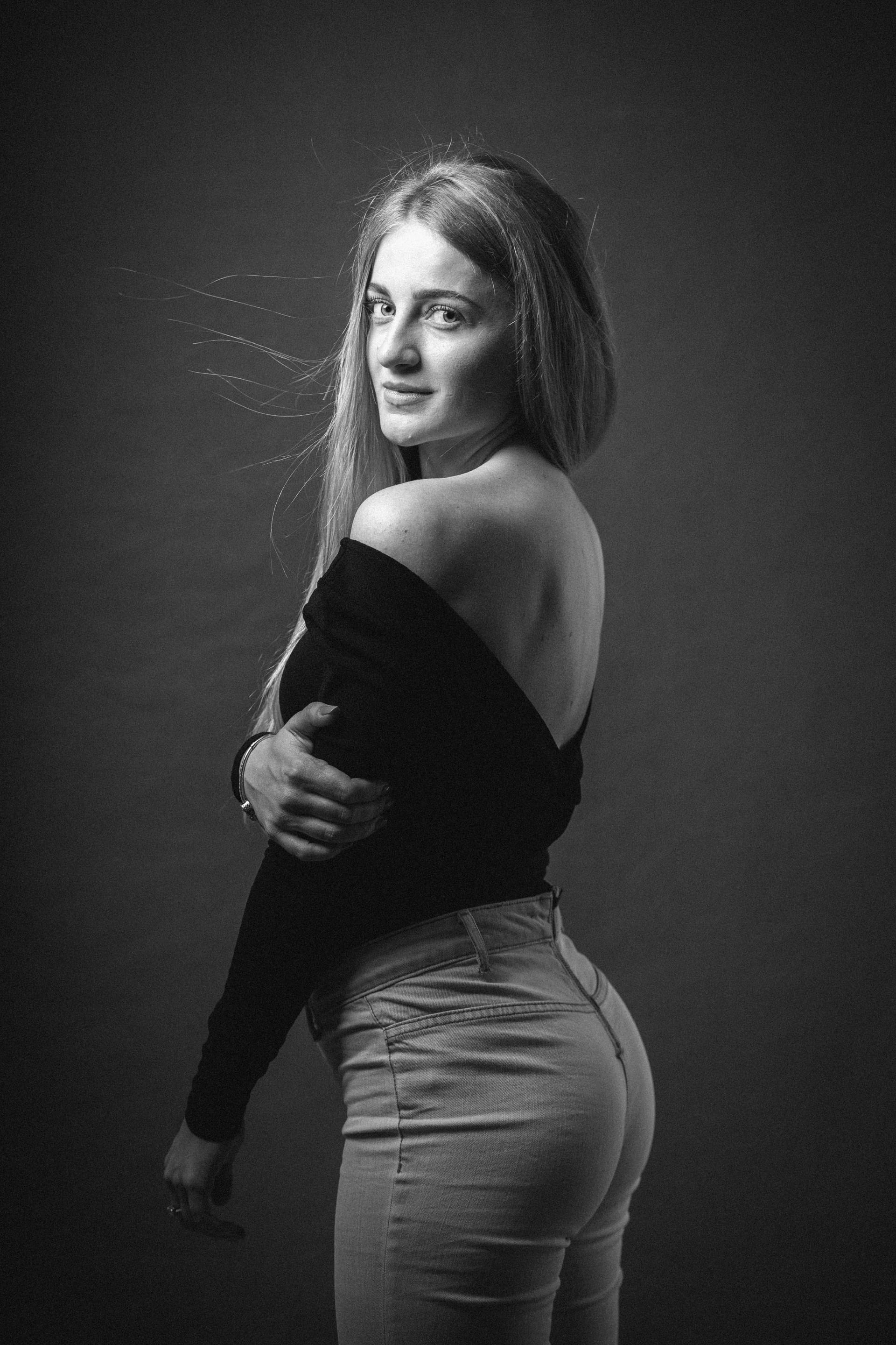 Vertical greyscale shot attractive blonde female posing while sitting barstool