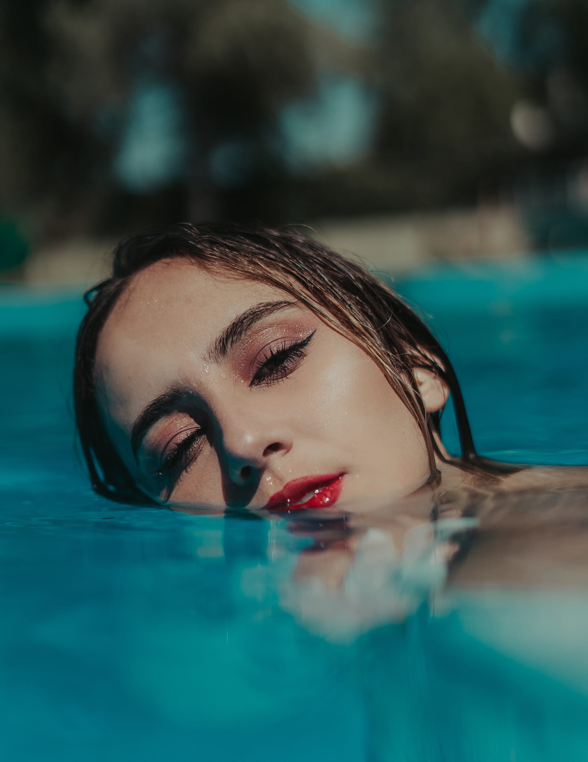Shallow focus young female wearing red lipstick pool sunny day