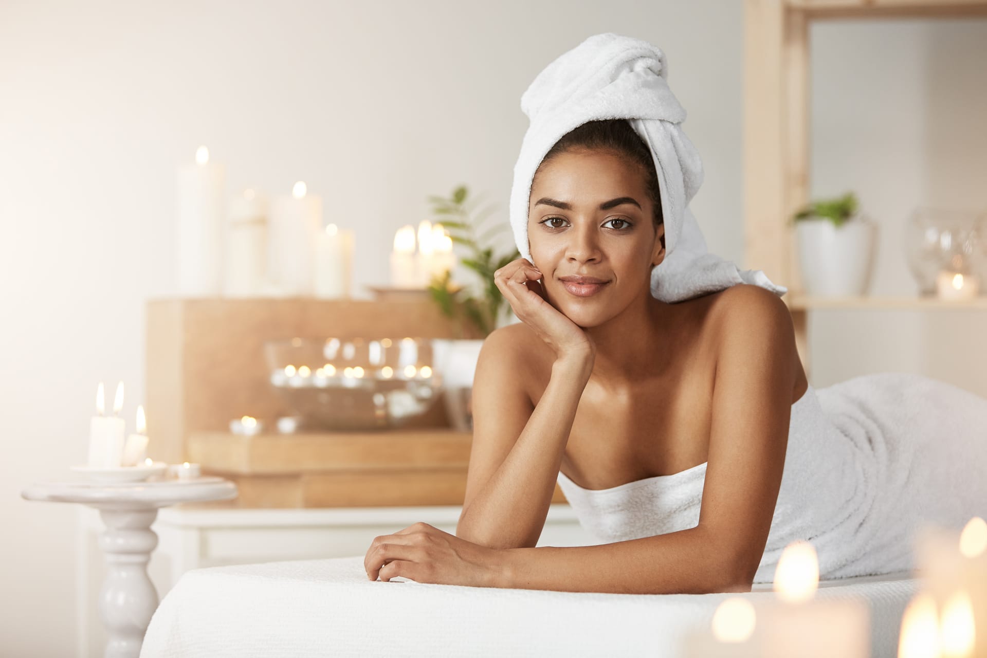 Portrait beautiful african woman with towel head smiling resting spa salon