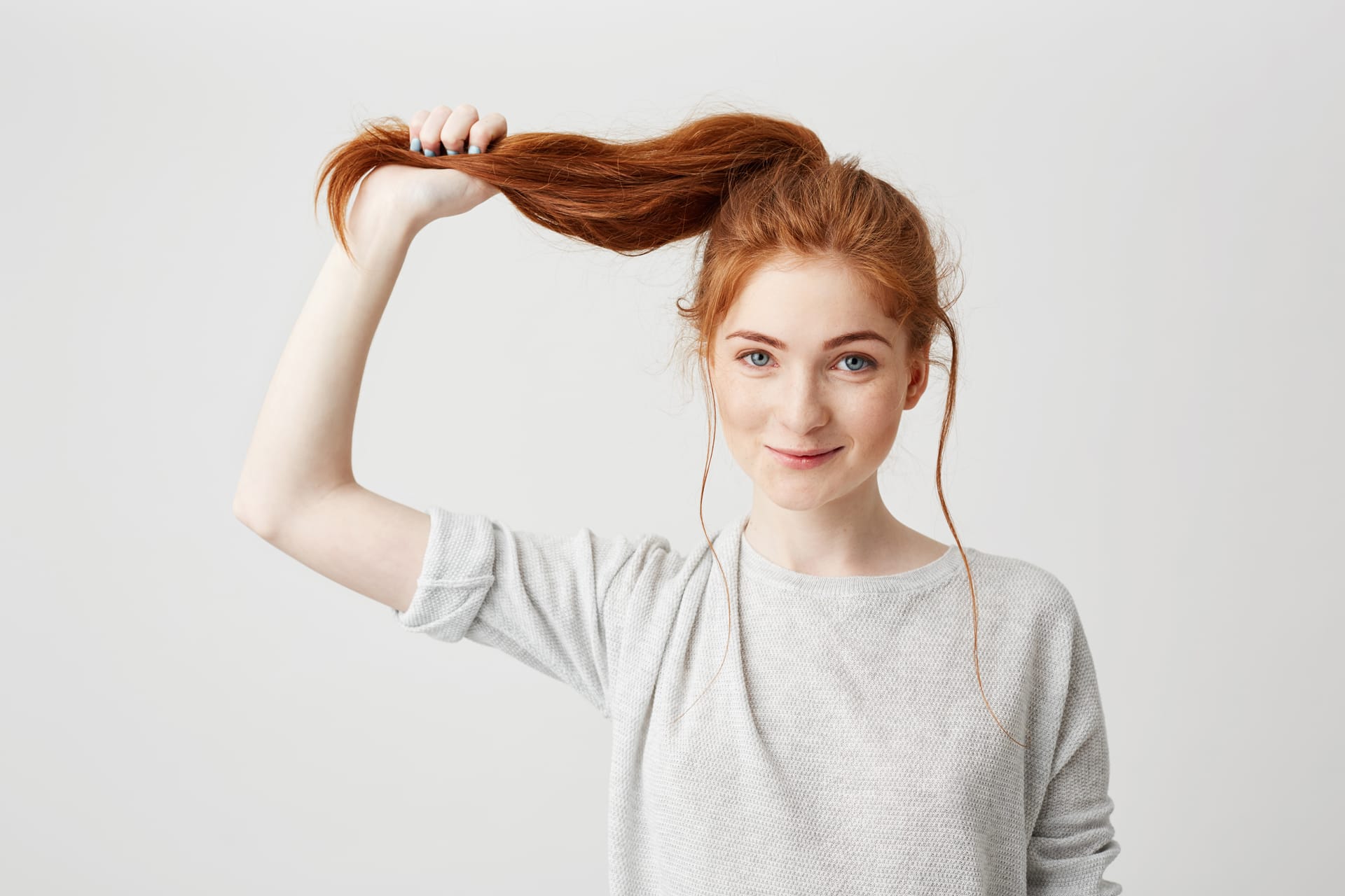 Portrait young beautiful redhead girl touching her hair tail