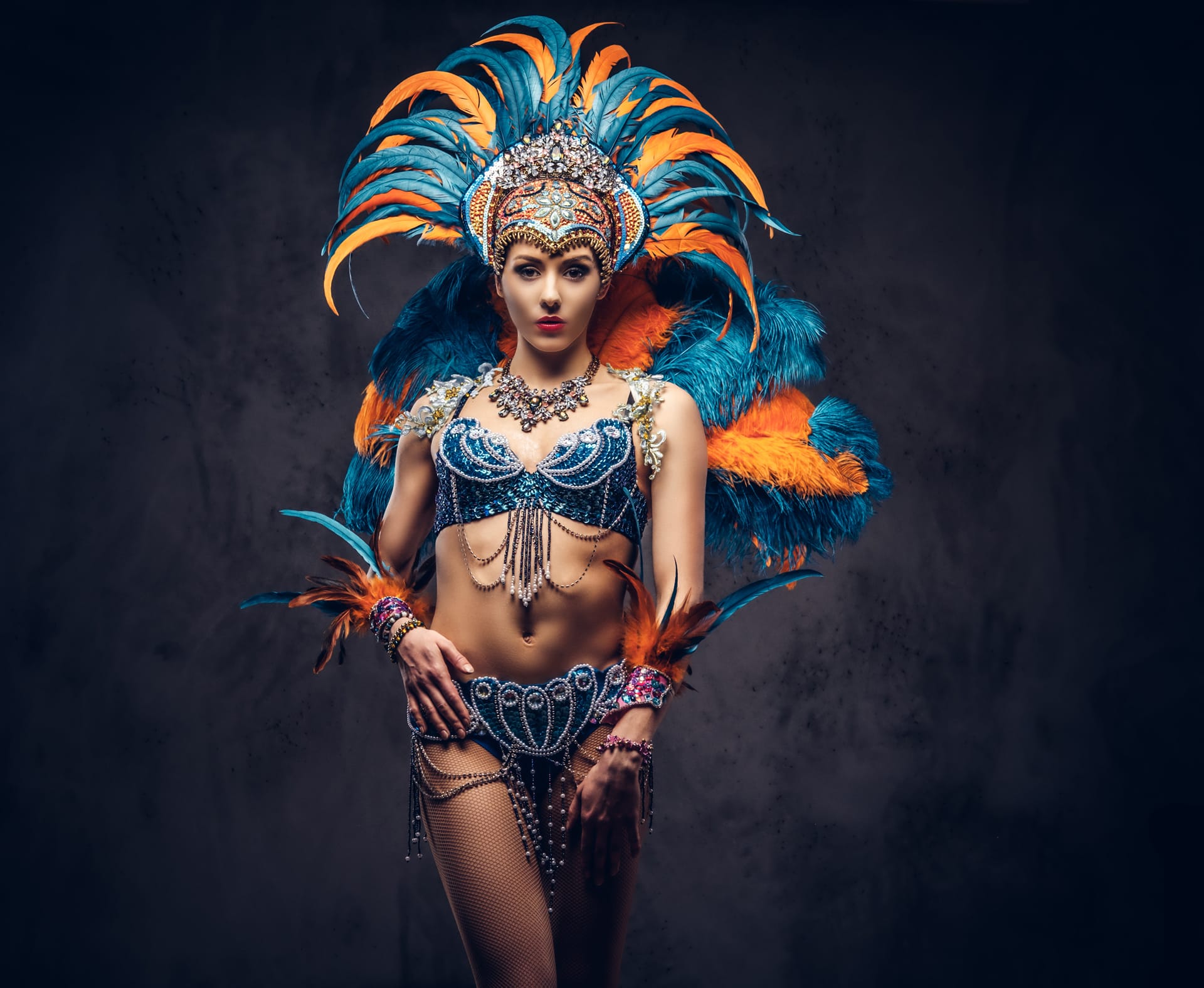 Studio portrait sexy female colorful sumptuous carnival feather suit posing dark background