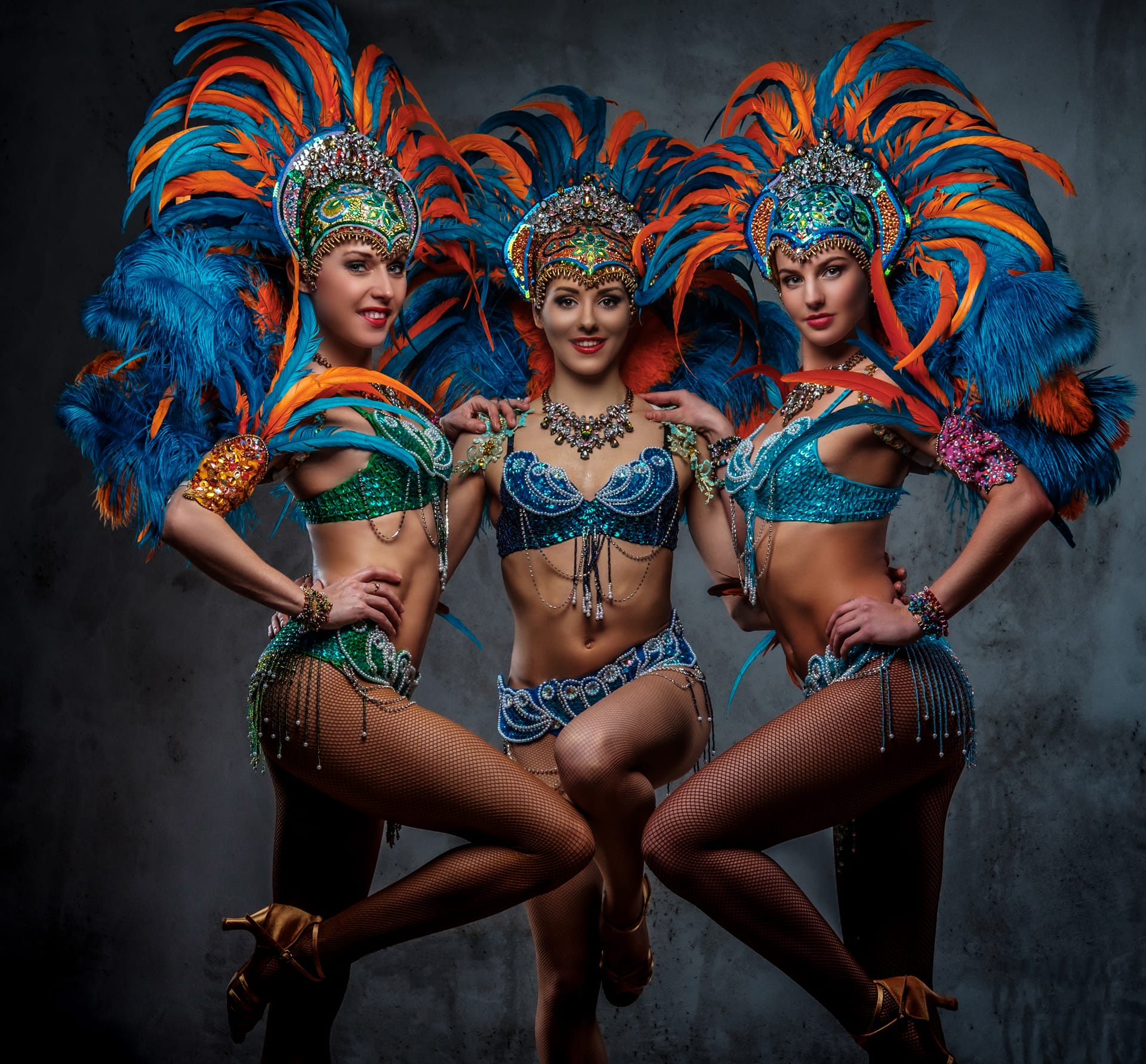 Group sexy girls colorful sumptuous carnival feather suit posing dark background