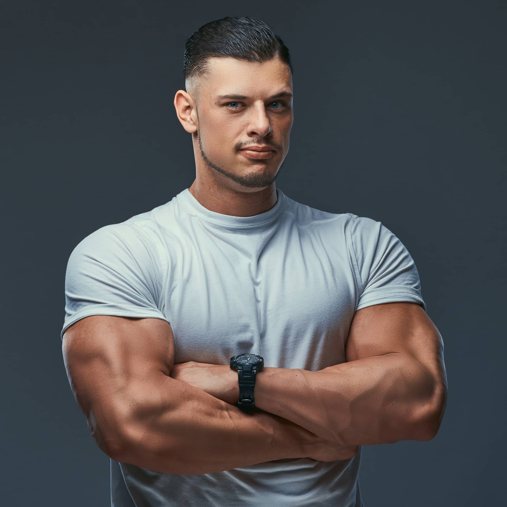 Bodybuilder sportswear standing with crossed arms studio isolated gray background