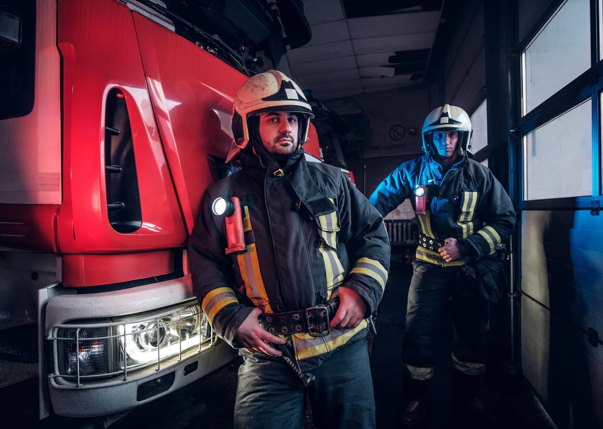 Firemen wearing protective uniform standing fire engine garage fire department
