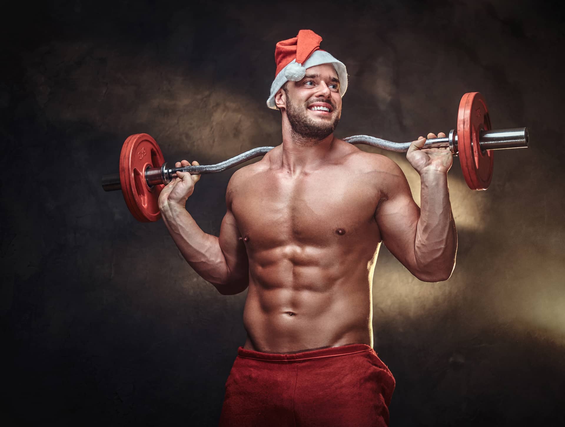 Fit man is holding barbell while posing photographer christmas time