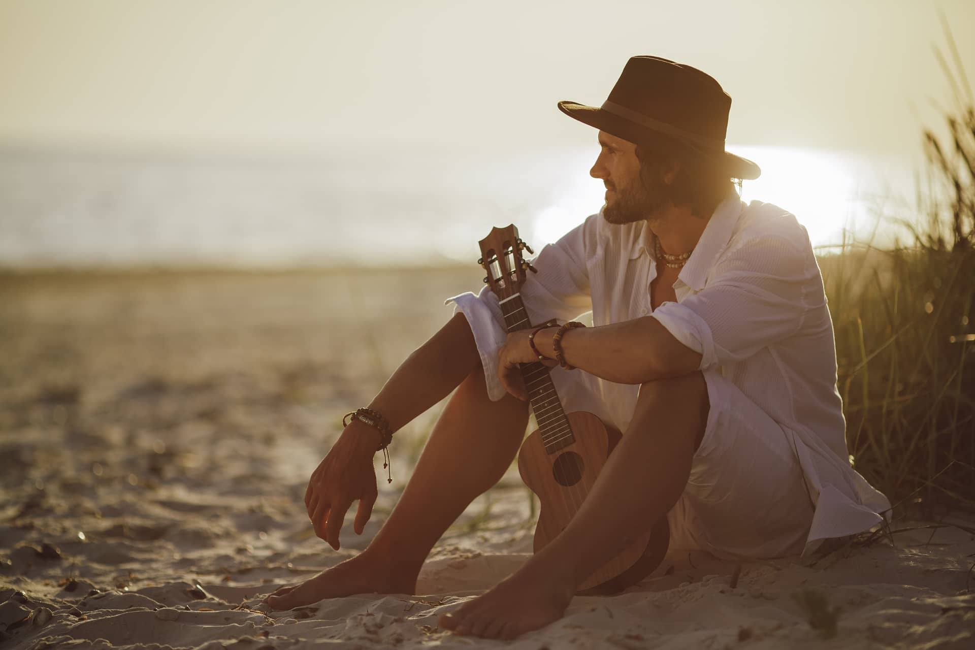 Man with ukulele during summer beach vacation near sea