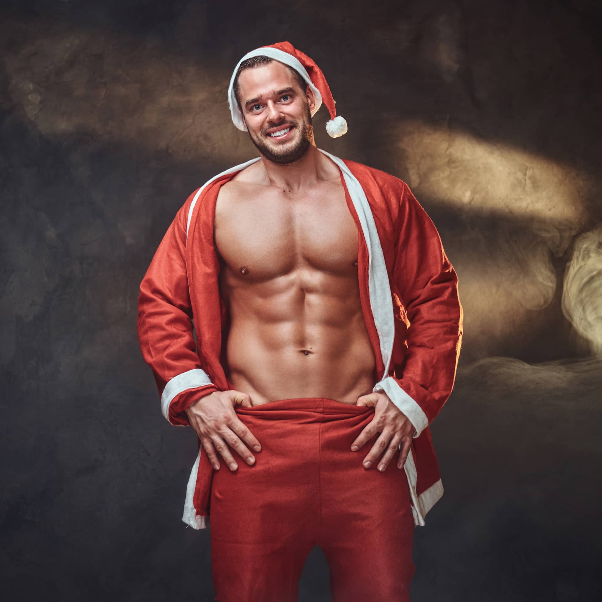 Sexy shirtless santa traditional red costume is posing photo studio