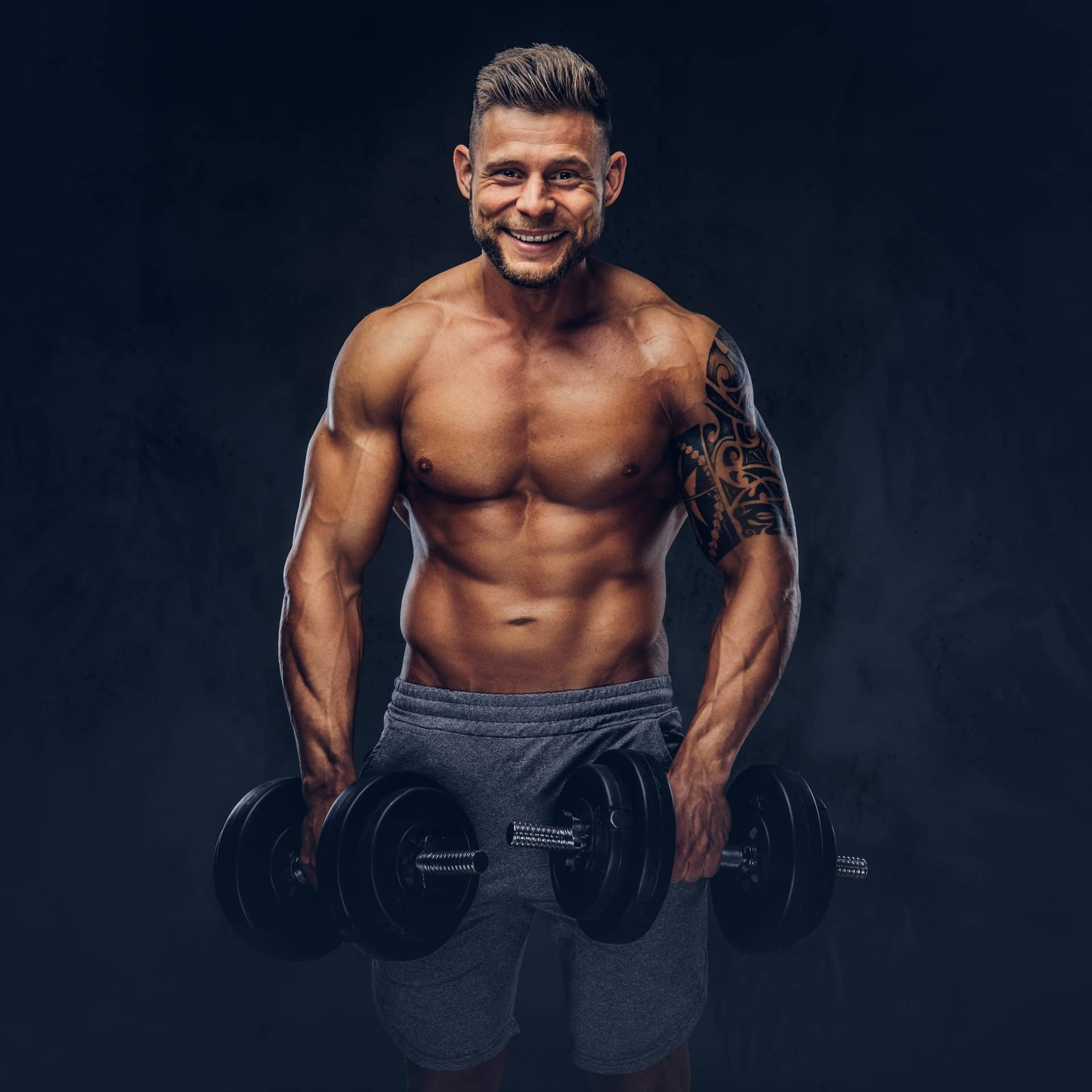Tattoo his arm doing exercises with dumbbells isolated dark background
