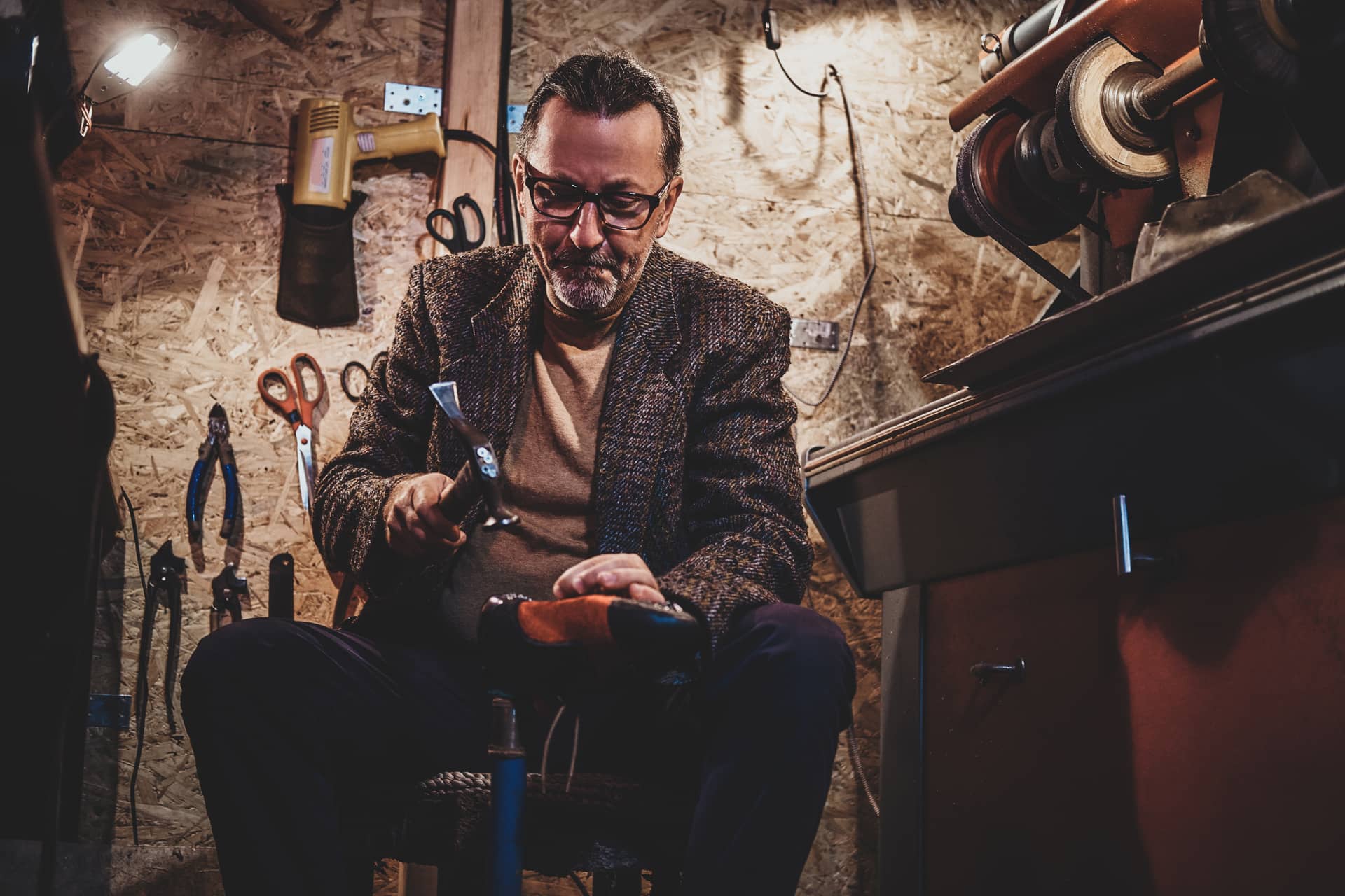 Man profile picture mature cobbler is fixing sole boots using hammer