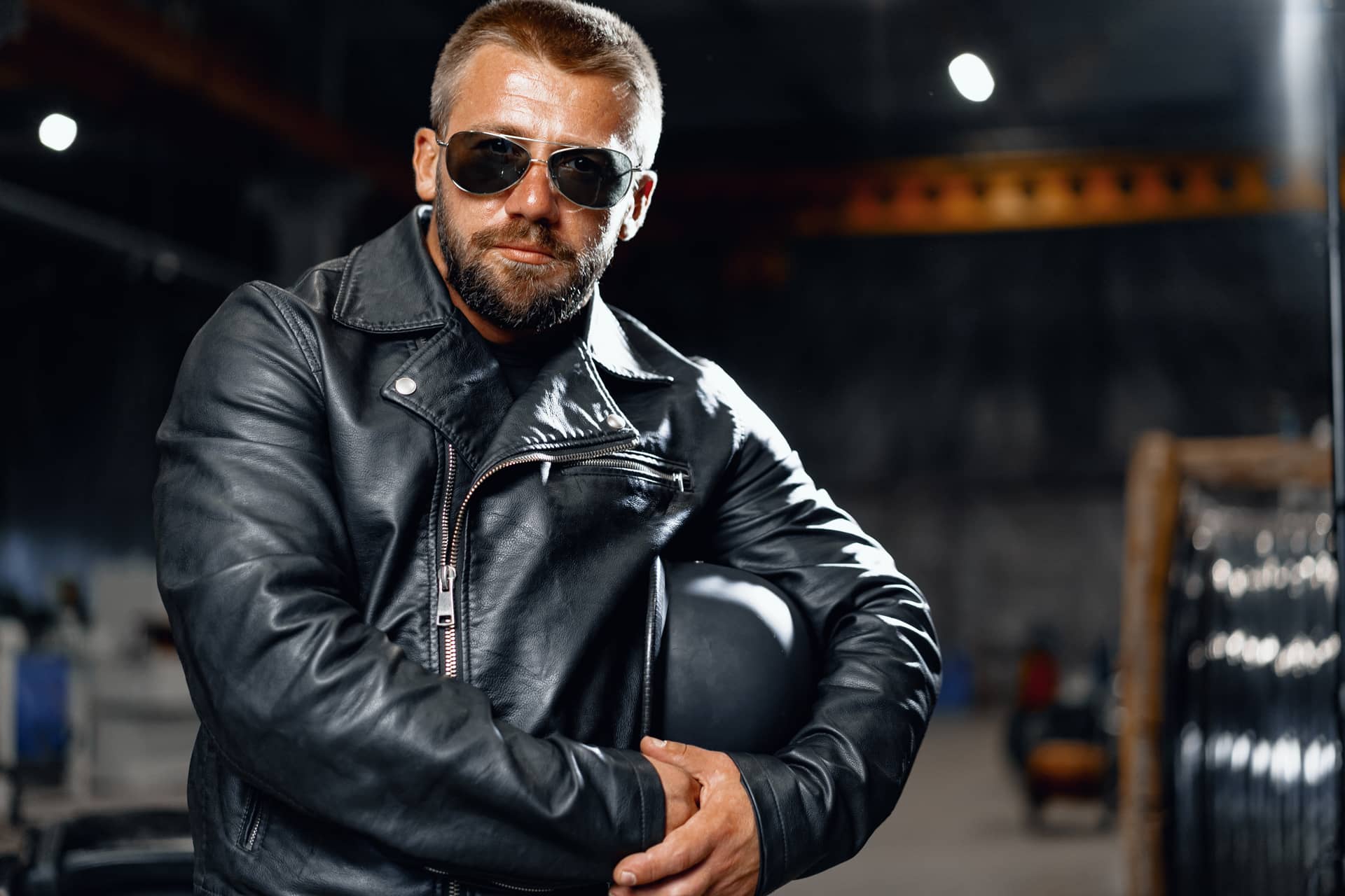 Portrait bearded man motocyclist dark sunglasses dark background