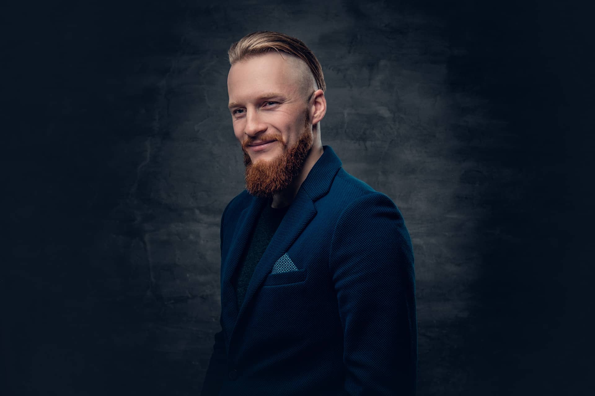 Portrait bearded redhead hipster male dressed blue jacket grey background