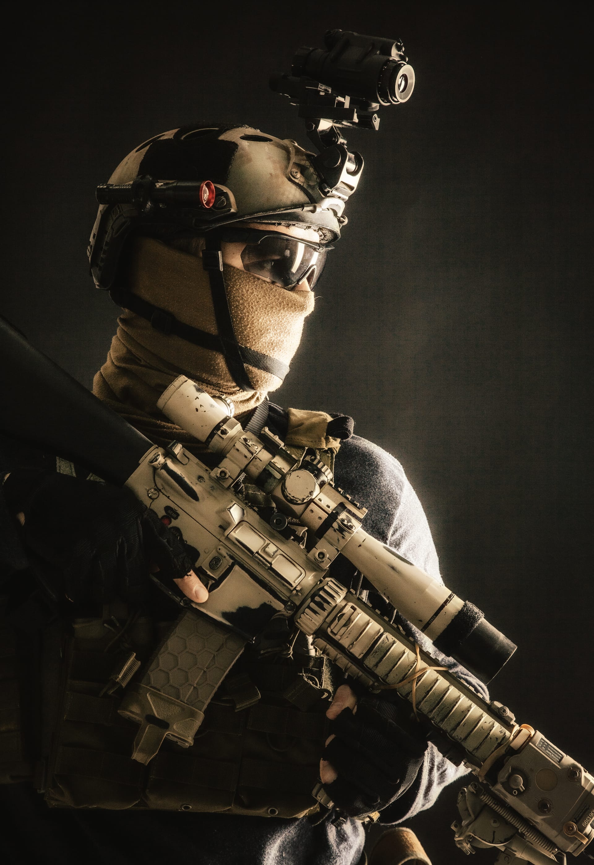 Soldier wearing helmet with thermal imager hiding face mask armed rifle