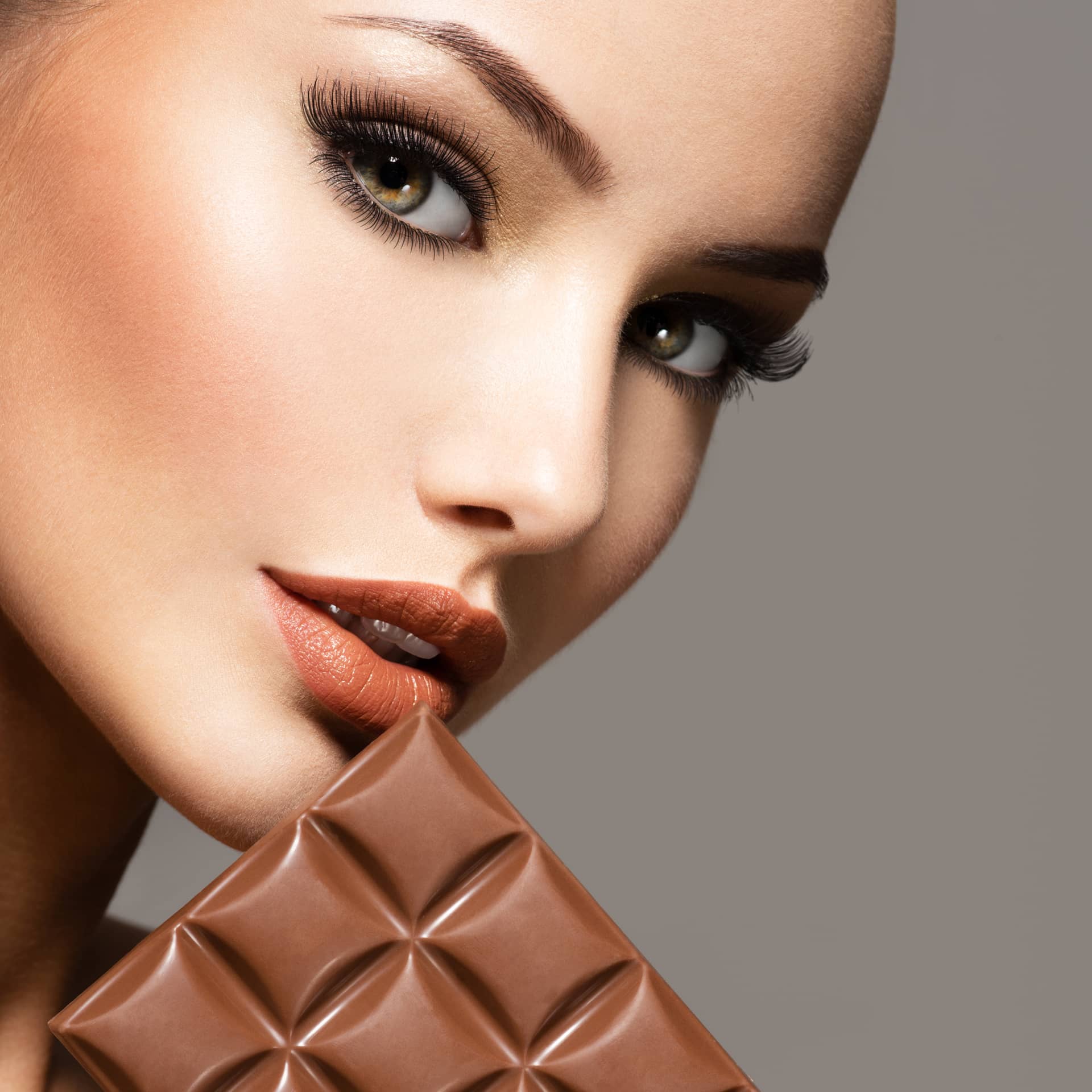 Portrait glamour beautiful woman with brown nails holds bar chocolate