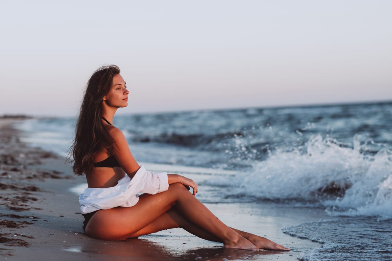 Related image young beautiful woman black bikini white shirt tanned body sits beach waves soft selective focus