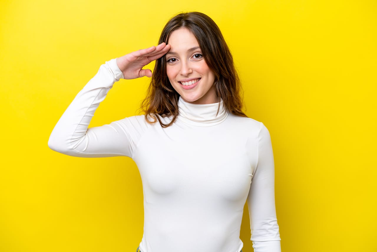 Related image young caucasian woman isolated yellow background saluting with hand with happy expression