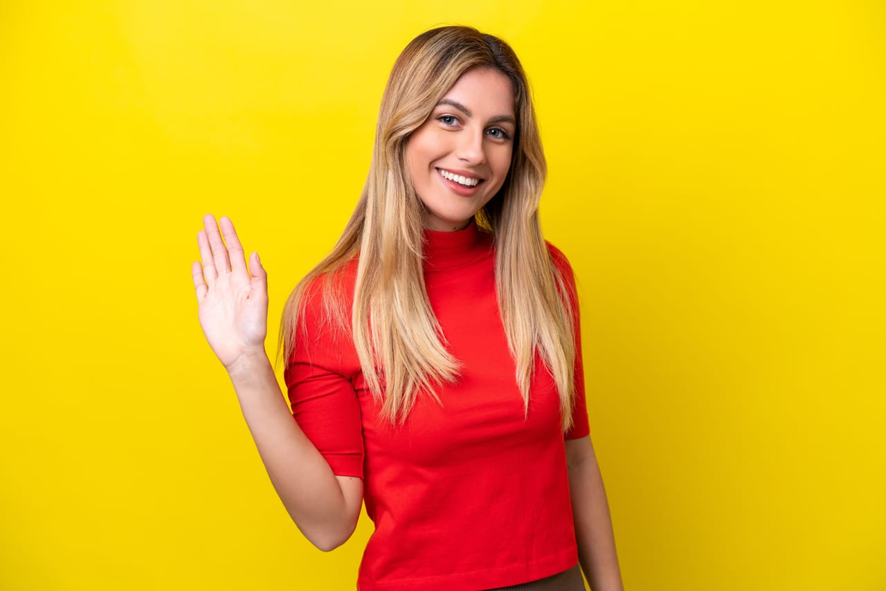 Related image young uruguayan woman isolated yellow background saluting with hand with happy expression